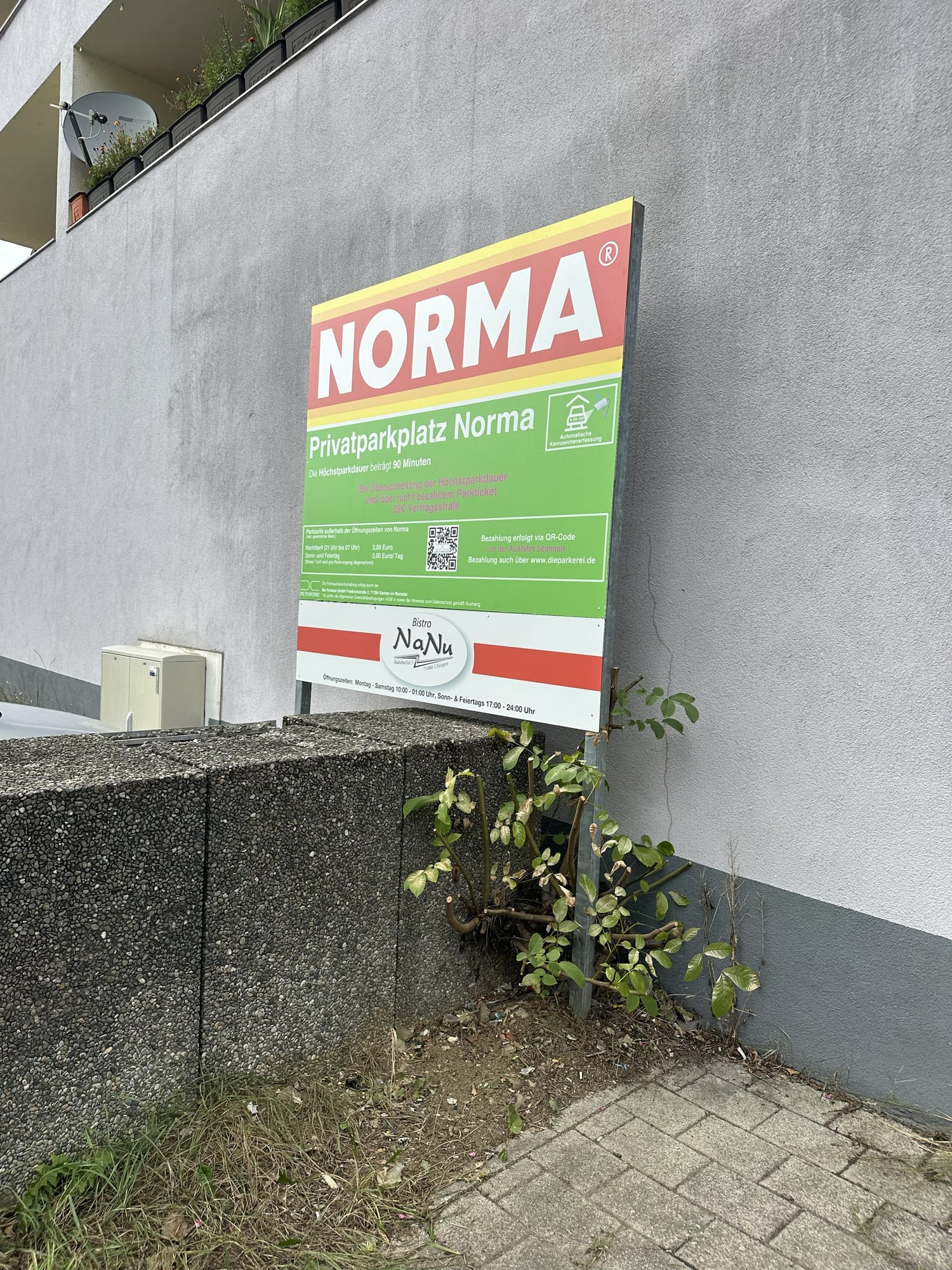 Kombiniertes Schild von Norma und der Parkerei mit den Feierabend- und Wochenendtarifen außerhalb der Öffnungszeiten