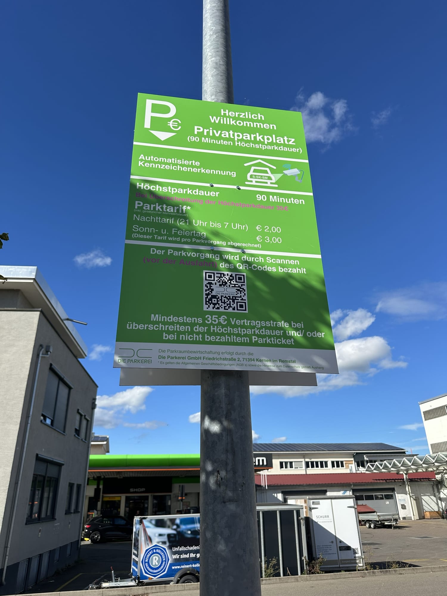 Grünes Hinweisschild der Parkerei mit automatisierter Kennzeichenerkennung, 90 Minuten Höchstparkdauer und QR-Code-Bezahlung auf einem Norma-Parkplatz
